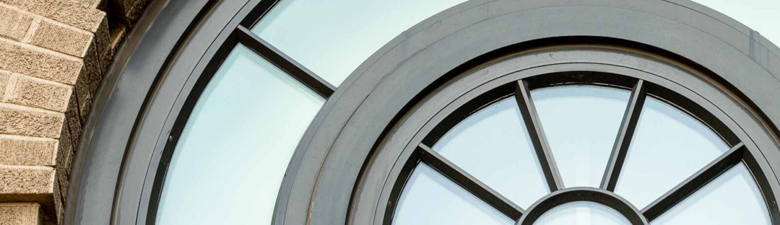 The top of a curved window with bricks framing the lefthand side.
